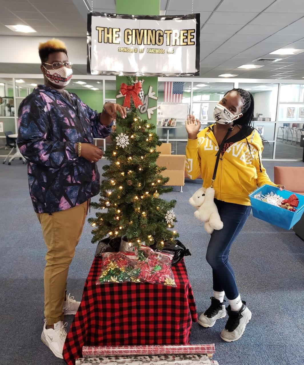 Two students stand on front of the "Giving Tree." 